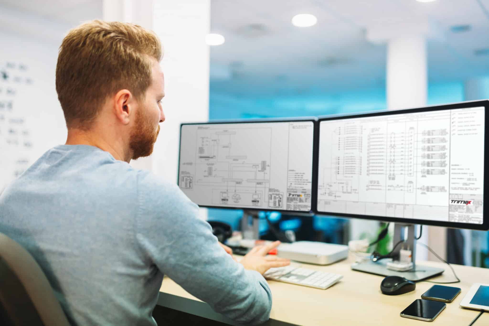 engineer reviewing electrical drawings on computer screens